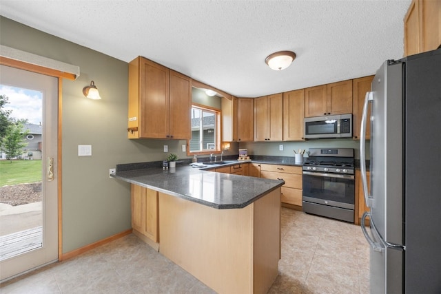 52 Thompson Dr, Palo, IA 52324 - kitchen featuring stainless steel appliances, a peninsula, dark countertops, a textured ceiling, and light tile patterned flooring