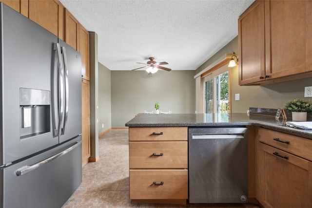 52 Thompson Dr, Palo, IA 52324 - kitchen featuring stainless steel appliances, a peninsula, dark countertops, brown cabinets, and a textured ceiling