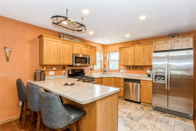 1017 Langenberg Ave, Iowa City, IA 52240 - kitchen featuring appliances with stainless steel finishes, light countertops, a peninsula, a breakfast bar, and light brown cabinets