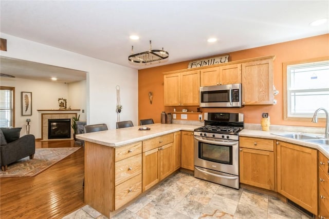 1017 Langenberg Ave, Iowa City, IA 52240 - kitchen with appliances with stainless steel finishes, a peninsula, light countertops, a tiled fireplace, and recessed lighting