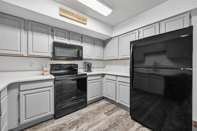 1211 Cambria Ct, Iowa City, IA 52246 - kitchen with black appliances, light wood-type flooring, gray cabinets, light countertops, and a textured ceiling