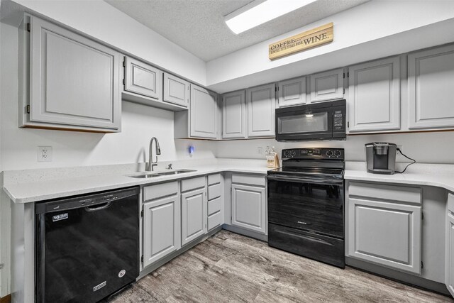 1211 Cambria Ct, Iowa City, IA 52246 - kitchen featuring black appliances, gray cabinets, light wood-style flooring, light countertops, and a textured ceiling
