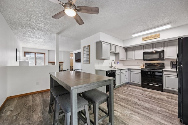 1211 Cambria Ct, Iowa City, IA 52246 - kitchen with black appliances, gray cabinets, light wood finished floors, a textured ceiling, and light countertops