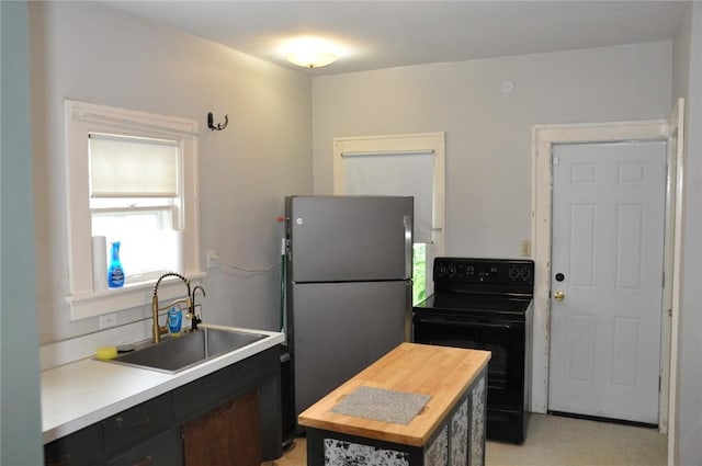 1535 SE 6th Ave, Cedar Rapids, IA 52403 - kitchen featuring black range with electric cooktop, freestanding refrigerator, butcher block countertops, and dark cabinetry