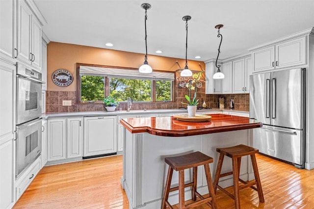 927 Southlawn Dr, Iowa City, IA 52245 - kitchen with appliances with stainless steel finishes, light wood-style floors, backsplash, hanging light fixtures, and white cabinets