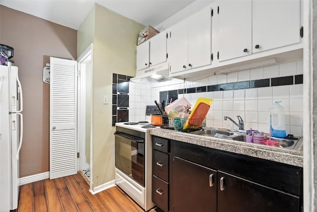 420 16th St NE, Cedar Rapids, IA 52402 - kitchen with white appliances, under cabinet range hood, white cabinetry, wood finished floors, and backsplash