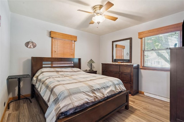 1039 31st St NE, Cedar Rapids, IA 52402 - bedroom featuring light wood-type flooring, a baseboard heating unit, and a ceiling fan