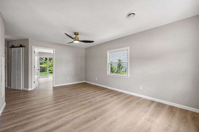 6404 Parkview Ave, Cedar Rapids, IA 52403 - empty room featuring light wood finished floors, ceiling fan, and a barn door