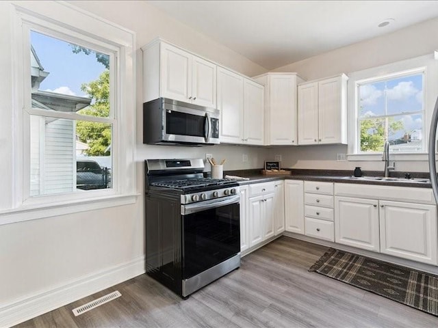 1308 A Ave NW, Cedar Rapids, IA 52405 - kitchen with stainless steel appliances, light wood finished floors, dark countertops, and white cabinets