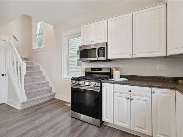 1308 A Ave NW, Cedar Rapids, IA 52405 - kitchen featuring stainless steel appliances, dark countertops, white cabinetry, and light wood-style floors