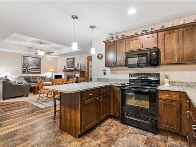 550 Meadow Oak Cir, Fairfax, IA 52228 - kitchen featuring black appliances, a peninsula, a tray ceiling, open floor plan, and a kitchen breakfast bar