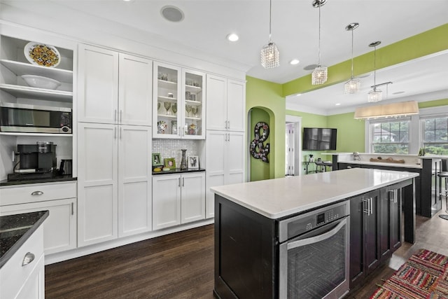 2144 Grande Ave SE, Cedar Rapids, IA 52403 - kitchen with stainless steel appliances, white cabinetry, dark wood-type flooring, pendant lighting, and glass insert cabinets