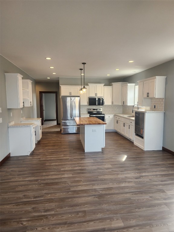 203 William Way, Newhall, IA 52315 - kitchen featuring appliances with stainless steel finishes, butcher block counters, dark wood-style floors, decorative backsplash, and white cabinetry