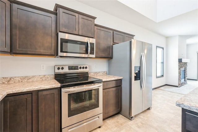 914 Deer Run Dr NE, Cedar Rapids, IA 52402 - kitchen featuring stainless steel appliances, dark brown cabinetry, light countertops, and a fireplace