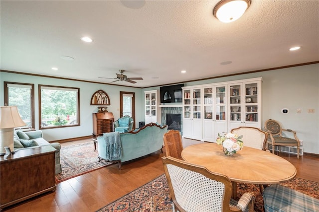 1579 Matterhorn Dr NE, Cedar Rapids, IA 52402 - dining space with ceiling fan, wood finished floors, a tile fireplace, recessed lighting, and crown molding