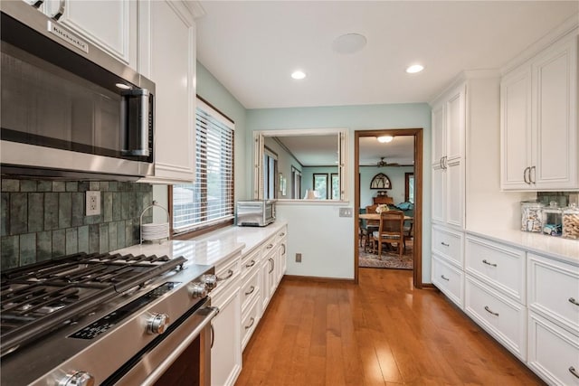 1579 Matterhorn Dr NE, Cedar Rapids, IA 52402 - kitchen with appliances with stainless steel finishes, white cabinets, light wood-type flooring, tasteful backsplash, and recessed lighting