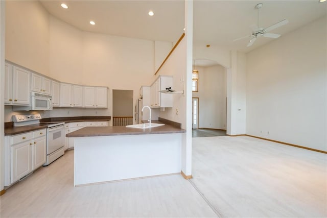 2500 Creekside Dr, Hiawatha, IA 52233 - kitchen featuring white appliances, a towering ceiling, white cabinetry, arched walkways, and a peninsula