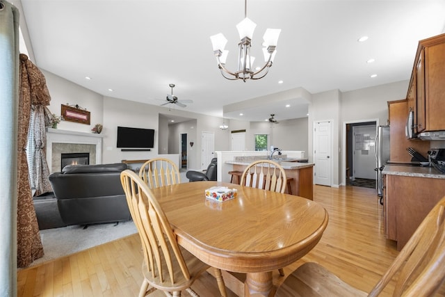 2515 Woodhill Dr SW, Cedar Rapids, IA 52404 - dining room with a glass covered fireplace, light wood finished floors, a ceiling fan, recessed lighting, and a chandelier