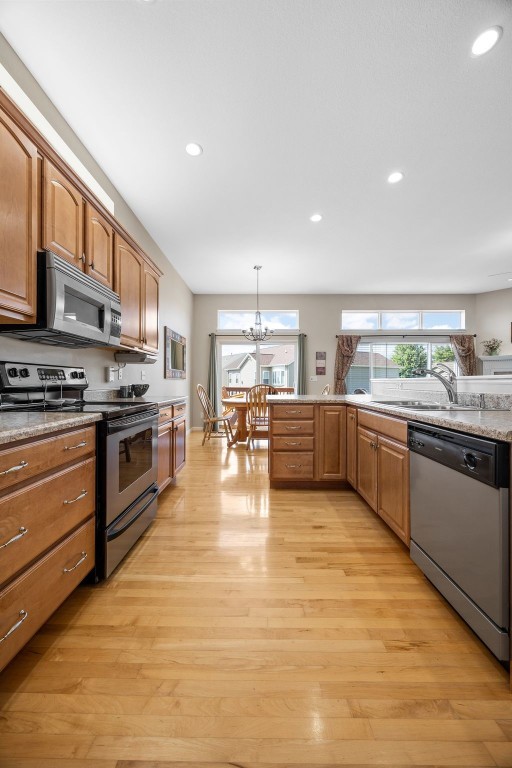 2515 Woodhill Dr SW, Cedar Rapids, IA 52404 - kitchen featuring stainless steel appliances, light wood-style flooring, a chandelier, recessed lighting, and brown cabinets
