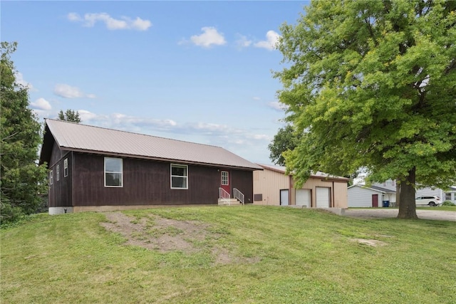 1009 W 1st St, Vinton, IA 52349 - view of front facade with entry steps, a front lawn, a garage, and a metal roof