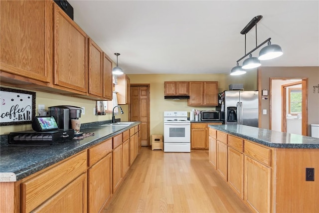 1009 W 1st St, Vinton, IA 52349 - kitchen featuring appliances with stainless steel finishes, light wood-style flooring, under cabinet range hood, and dark countertops
