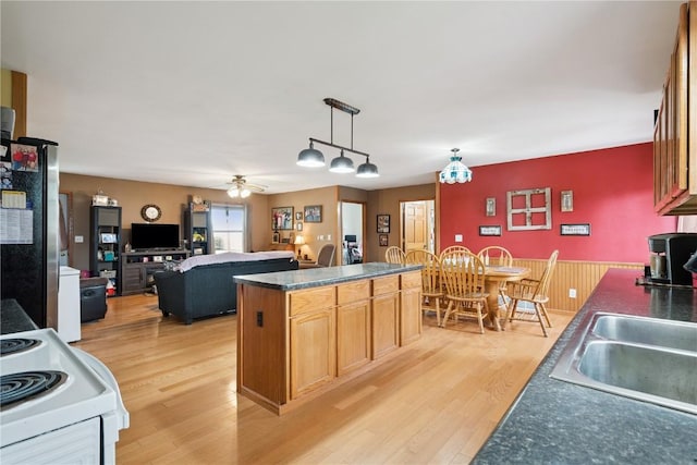 1009 W 1st St, Vinton, IA 52349 - kitchen featuring freestanding refrigerator, dark countertops, white electric range oven, light wood-type flooring, and a center island