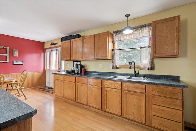 1009 W 1st St, Vinton, IA 52349 - kitchen featuring dark countertops, brown cabinets, light wood-type flooring, wainscoting, and hanging light fixtures