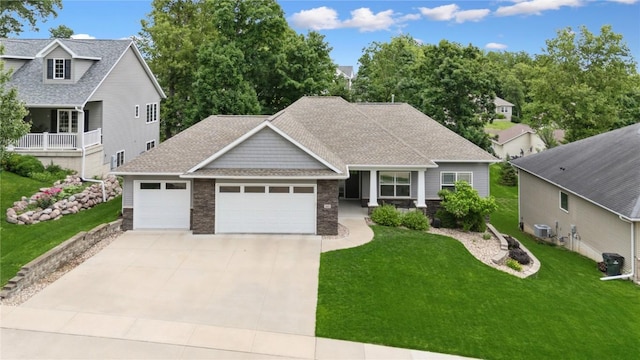 2021 Andrew Charles Dr NW, Cedar Rapids, IA 52405 - view of front facade with a garage, a front yard, driveway, a shingled roof, and stone siding