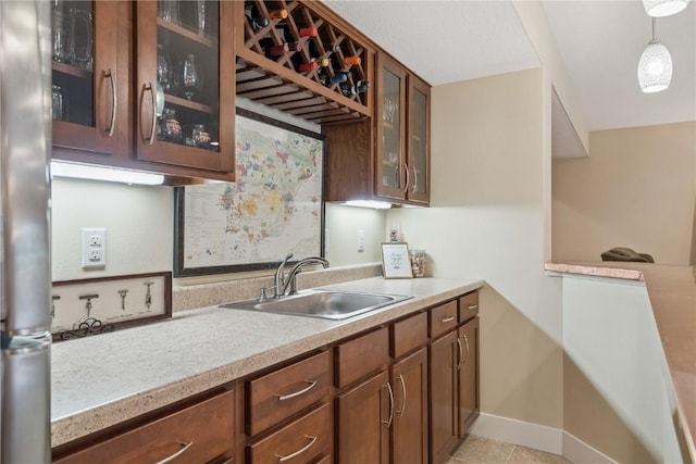 2021 Andrew Charles Dr NW, Cedar Rapids, IA 52405 - kitchen with light countertops, freestanding refrigerator, hanging light fixtures, glass insert cabinets, and brown cabinetry