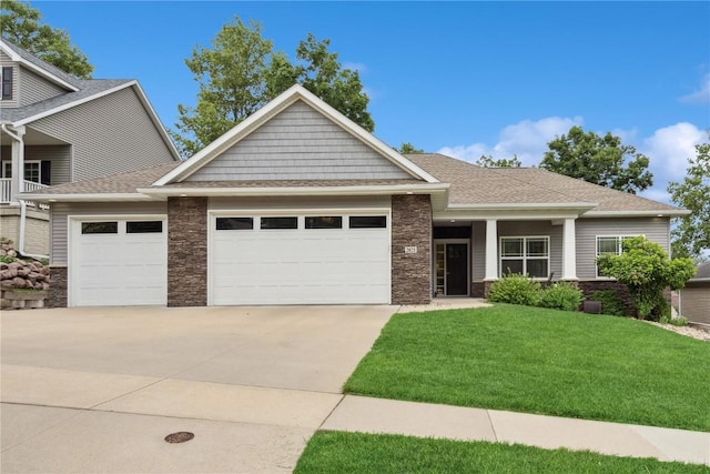 2021 Andrew Charles Dr NW, Cedar Rapids, IA 52405 - craftsman-style home with an attached garage, stone siding, driveway, a front lawn, and roof with shingles