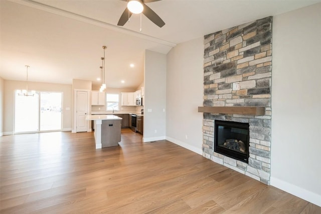 6188 Cope Dr, Marion, IA 52302 - unfurnished living room with lofted ceiling, ceiling fan, a fireplace, light wood-style floors, and a chandelier