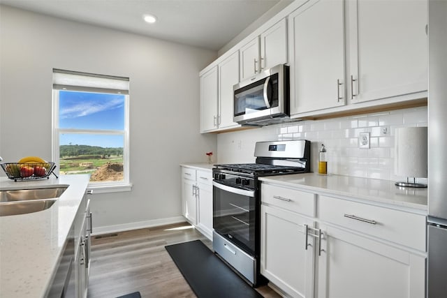 717 E Bear Dr, Tiffin, IA 52340 - kitchen featuring stainless steel appliances, tasteful backsplash, light wood-style flooring, white cabinetry, and recessed lighting