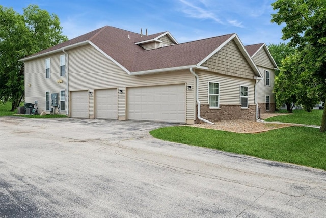 4405 Westchester Dr Unit B, Cedar Rapids, IA 52402 - view of home's exterior featuring driveway, a garage, brick siding, a shingled roof, and a yard
