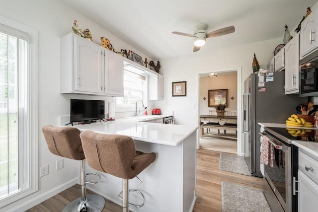 4405 Westchester Dr Unit B, Cedar Rapids, IA 52402 - kitchen featuring stainless steel electric range, white cabinetry, a peninsula, light wood-style floors, and ceiling fan