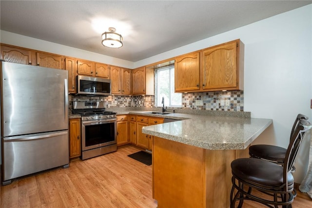 6514 Fox Run Dr SW, Cedar Rapids, IA 52404 - kitchen featuring appliances with stainless steel finishes, a peninsula, light wood finished floors, a kitchen bar, and tasteful backsplash