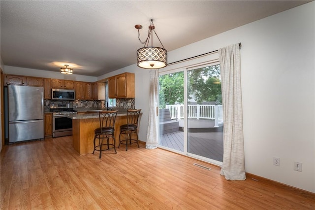 6514 Fox Run Dr SW, Cedar Rapids, IA 52404 - kitchen with stainless steel appliances, light wood-style flooring, backsplash, a peninsula, and brown cabinets