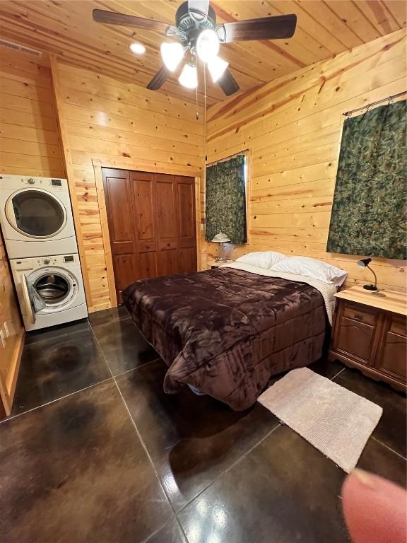 140 Falcon Dr, Montezuma, IA 50171 - bedroom with stacked washing machine and dryer, wooden walls, a ceiling fan, wood ceiling, and concrete flooring