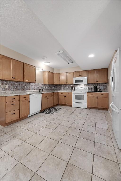 114 Therese Ave, Anamosa, IA 52205 - kitchen with white appliances, decorative backsplash, light countertops, and light tile patterned floors