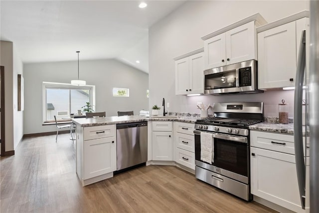 713 Hillside Dr, Tiffin, IA 52340 - kitchen featuring stainless steel appliances, a peninsula, lofted ceiling, white cabinetry, and light wood-type flooring
