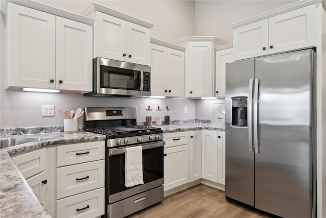 713 Hillside Dr, Tiffin, IA 52340 - kitchen featuring appliances with stainless steel finishes, white cabinets, light wood-style floors, and light stone countertops