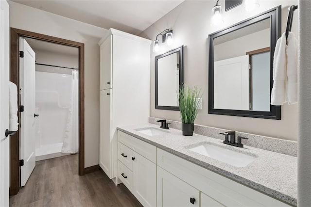 713 Hillside Dr, Tiffin, IA 52340 - bathroom with double vanity, wood finished floors, and a shower with shower curtain