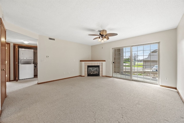 3120 Wilson Ave SW Unit 2, Cedar Rapids, IA 52404 - unfurnished living room featuring stacked washer / dryer, light carpet, ceiling fan, a fireplace, and a textured ceiling