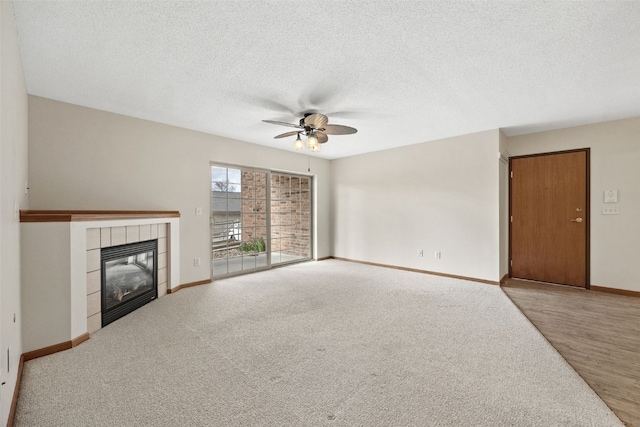3120 Wilson Ave SW Unit 2, Cedar Rapids, IA 52404 - unfurnished living room featuring a ceiling fan, a tiled fireplace, a textured ceiling, and wood finished floors