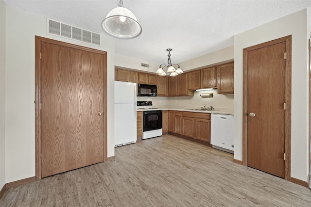 3120 Wilson Ave SW Unit 2, Cedar Rapids, IA 52404 - kitchen featuring white appliances, light countertops, light wood finished floors, pendant lighting, and brown cabinets