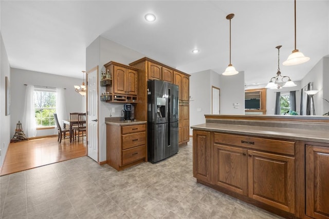 712 Willow Ct, Solon, IA 52333 - kitchen with fridge with ice dispenser, a chandelier, brown cabinets, and pendant lighting