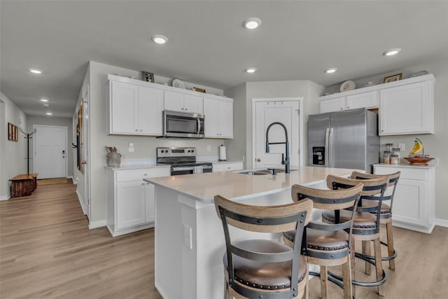 305 Sumac Dr, Palo, IA 52324 - kitchen with stainless steel appliances, light countertops, light wood-type flooring, a center island with sink, and white cabinets