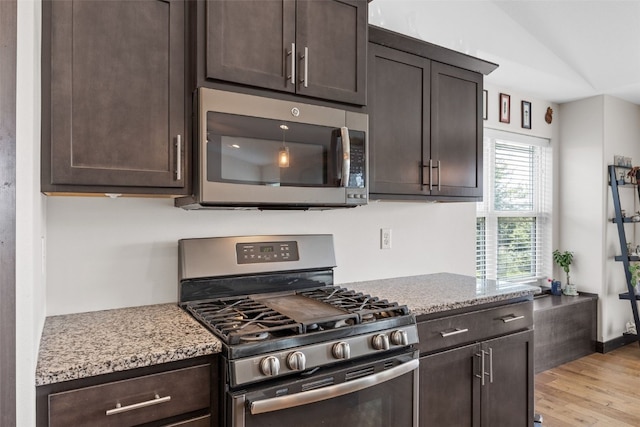 210 Northgate St NW, Shellsburg, IA 52332 - kitchen with appliances with stainless steel finishes, dark brown cabinetry, light wood-style flooring, light stone counters, and vaulted ceiling