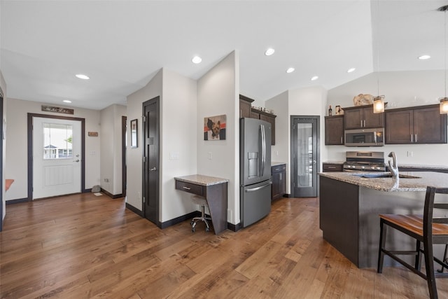 210 Northgate St NW, Shellsburg, IA 52332 - kitchen with appliances with stainless steel finishes, dark brown cabinetry, wood finished floors, light stone countertops, and a breakfast bar