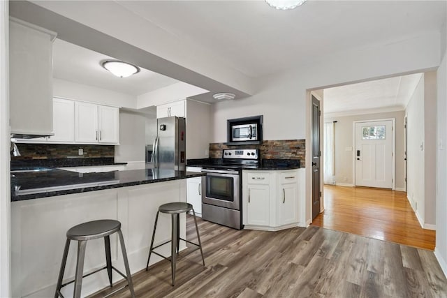 3642 Redbud Rd NE, Cedar Rapids, IA 52402 - kitchen with stainless steel appliances, tasteful backsplash, white cabinetry, and light wood finished floors