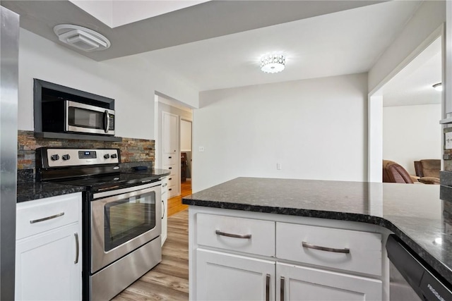 3642 Redbud Rd NE, Cedar Rapids, IA 52402 - kitchen featuring stainless steel appliances, light wood-type flooring, decorative backsplash, white cabinetry, and dark stone countertops